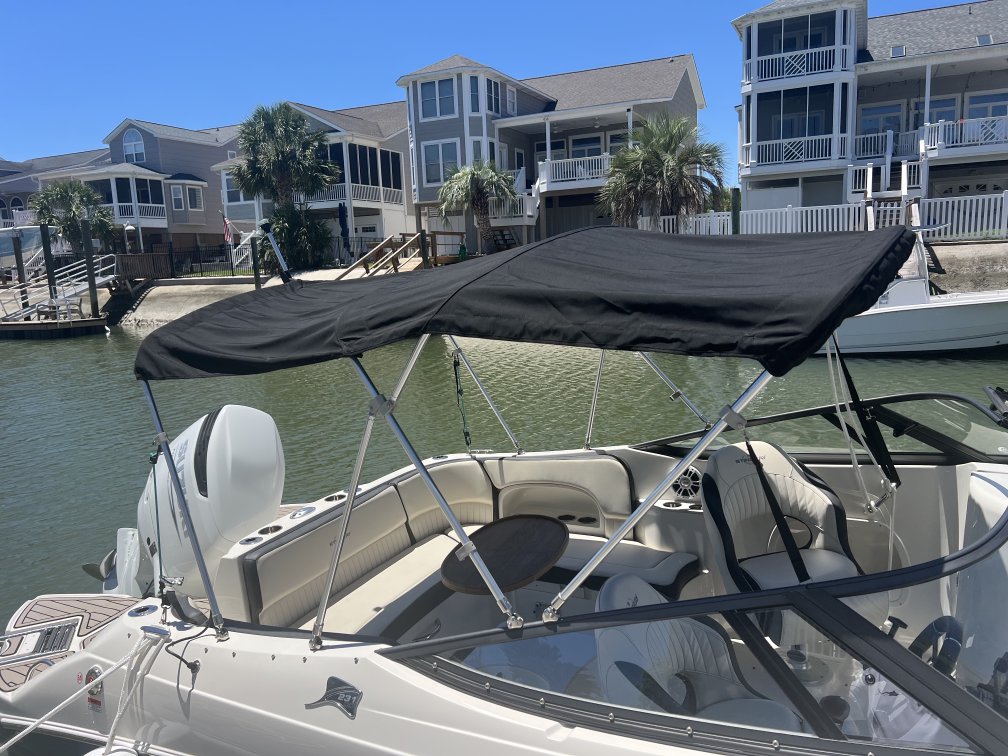 Classic black Bimini top on a white boat at a sunny coastal canal